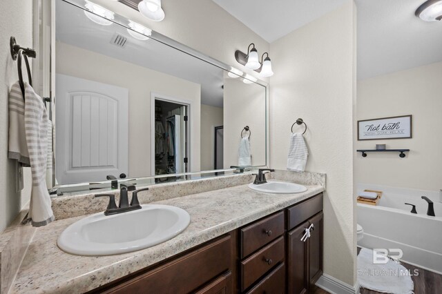 full bath featuring a garden tub, visible vents, a sink, and double vanity