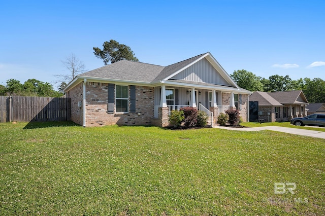 view of front of property featuring fence, a front lawn, covered porch, and brick siding