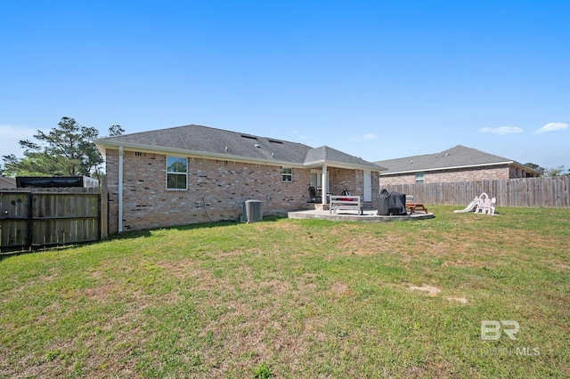 back of house with brick siding, a lawn, a fenced backyard, and a patio