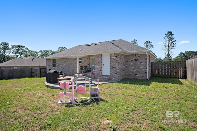 rear view of property with brick siding, a yard, a patio area, and a fenced backyard