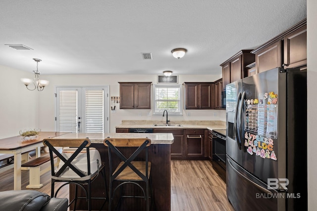 kitchen featuring a sink, black range with electric cooktop, stainless steel fridge with ice dispenser, dark brown cabinetry, and light countertops