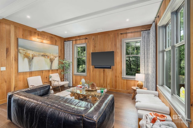 living room featuring beam ceiling, wooden walls, and light hardwood / wood-style flooring