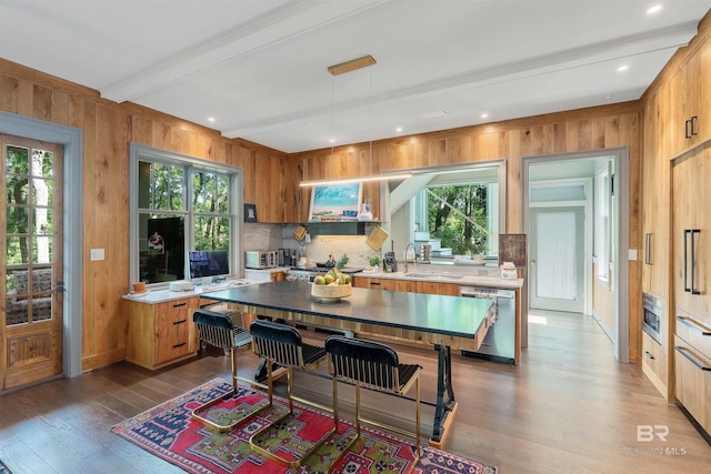 kitchen with hardwood / wood-style floors, beamed ceiling, dishwasher, and hanging light fixtures