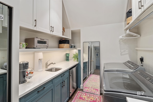 kitchen featuring wood-type flooring, washing machine and clothes dryer, white cabinets, sink, and blue cabinets