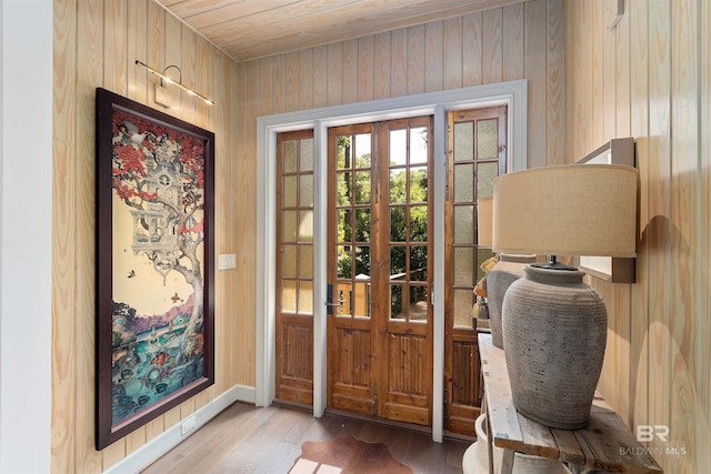 doorway with wood-type flooring, wood walls, and french doors