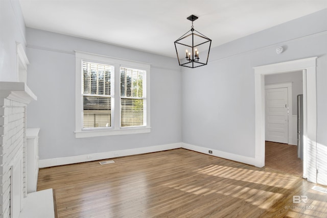 unfurnished dining area with an inviting chandelier and wood-type flooring