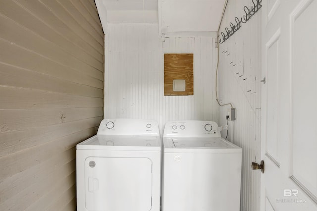 clothes washing area featuring washing machine and clothes dryer and wooden walls