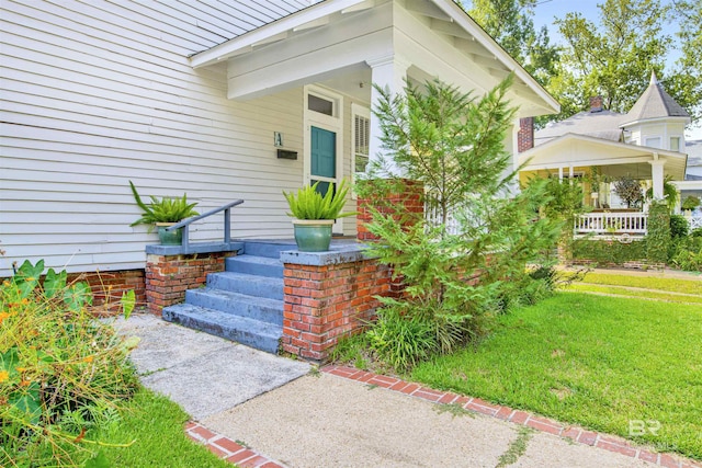 entrance to property with a porch and a lawn