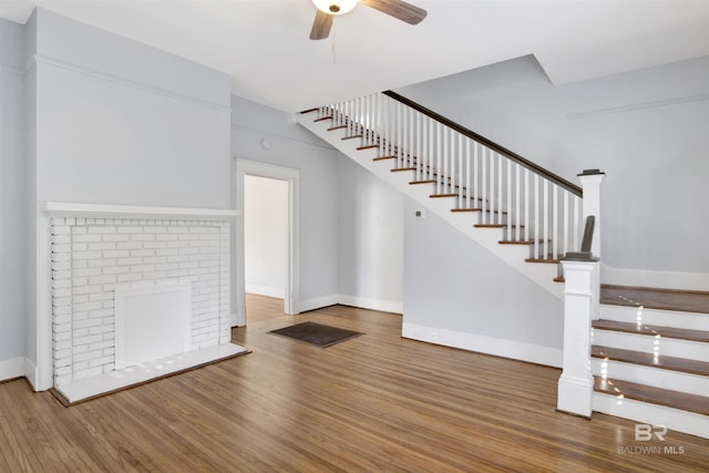 interior space featuring wood-type flooring, a fireplace, and ceiling fan