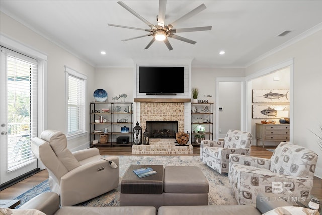 living room featuring hardwood / wood-style floors, a brick fireplace, crown molding, and ceiling fan