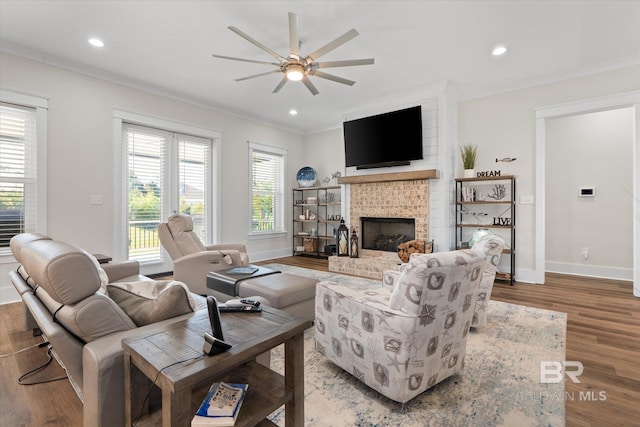 living room with ceiling fan, crown molding, a fireplace, and hardwood / wood-style floors