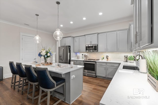 kitchen with dark hardwood / wood-style flooring, a breakfast bar area, a kitchen island, stainless steel appliances, and decorative light fixtures