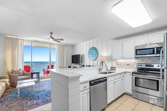 kitchen featuring kitchen peninsula, white cabinetry, sink, and appliances with stainless steel finishes