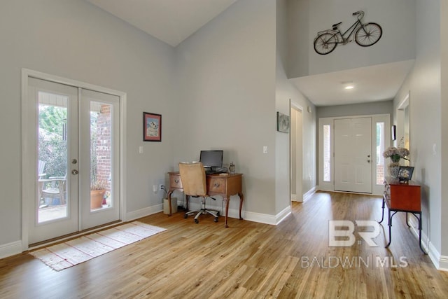 entrance foyer featuring a towering ceiling, french doors, and light wood-type flooring