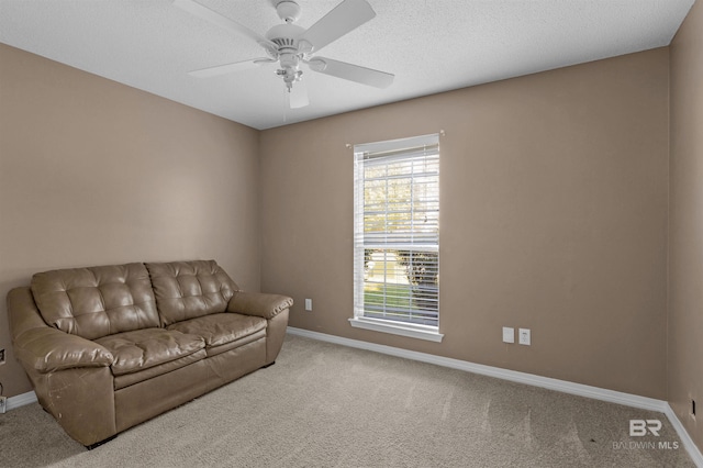 living area featuring carpet flooring, a textured ceiling, a ceiling fan, and baseboards