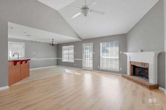 unfurnished living room featuring a brick fireplace, a healthy amount of sunlight, light wood-type flooring, and baseboards