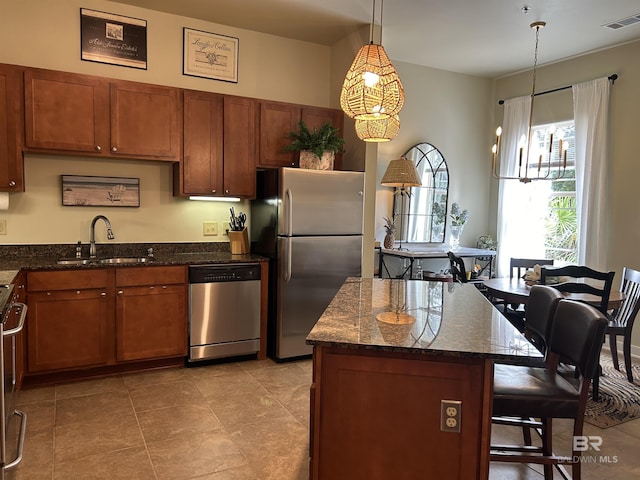 kitchen with a breakfast bar, visible vents, appliances with stainless steel finishes, a sink, and dark stone countertops