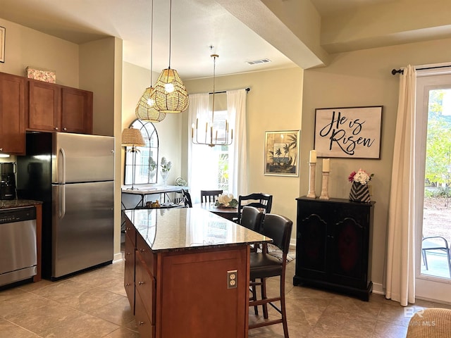 kitchen with visible vents, appliances with stainless steel finishes, a breakfast bar, dark stone countertops, and a center island