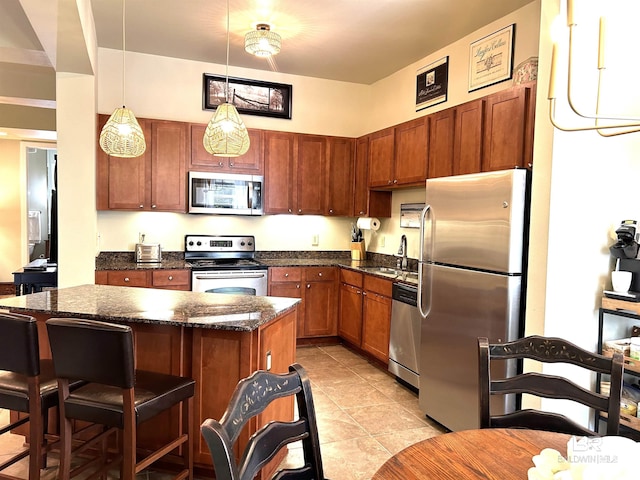 kitchen with a breakfast bar, a sink, a kitchen island, hanging light fixtures, and appliances with stainless steel finishes