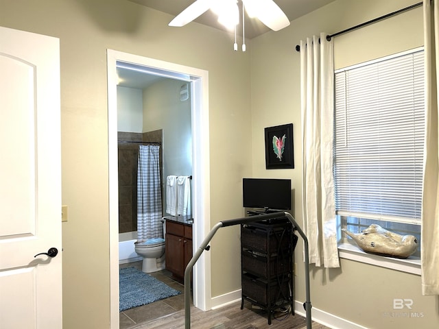 interior space with toilet, shower / tub combo, ceiling fan, wood finished floors, and baseboards