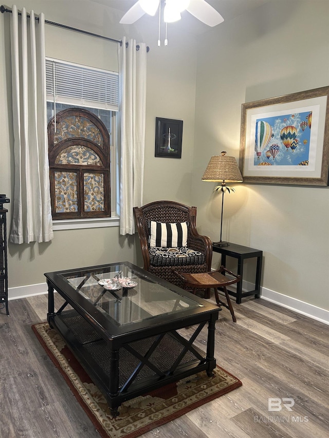 living area featuring a ceiling fan, baseboards, and wood finished floors