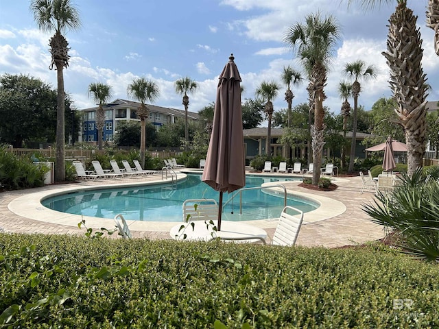 community pool with a patio area and fence