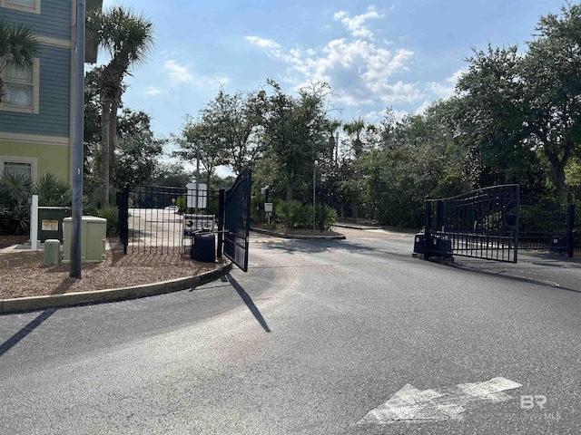 view of street featuring a gate, curbs, and a gated entry