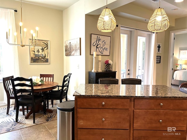 kitchen featuring french doors, brown cabinets, hanging light fixtures, and dark stone countertops