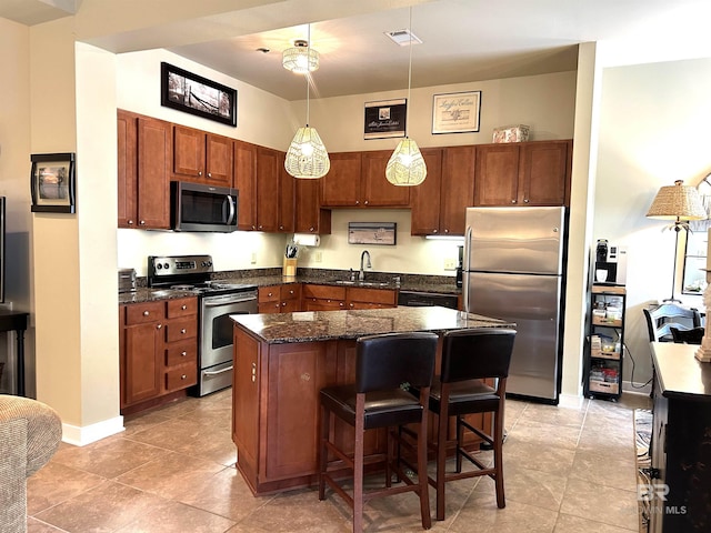 kitchen featuring visible vents, a kitchen island, a breakfast bar area, appliances with stainless steel finishes, and a sink