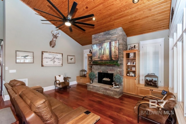 living room featuring baseboards, ceiling fan, a stone fireplace, wooden ceiling, and wood finished floors