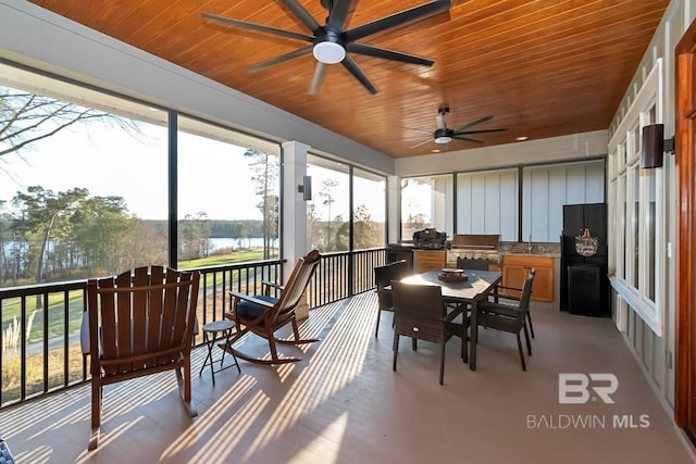 sunroom featuring wooden ceiling, a ceiling fan, and a healthy amount of sunlight