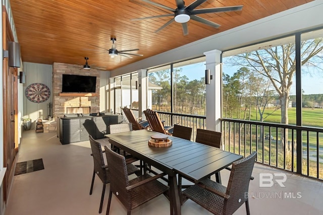 sunroom with wood ceiling, ceiling fan, and a fireplace