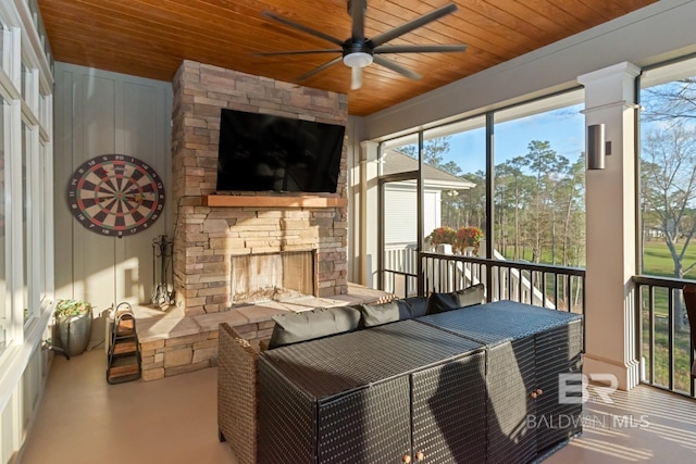 sunroom / solarium featuring a stone fireplace, wood ceiling, and ceiling fan