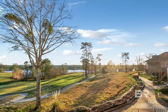 surrounding community with a yard, a water view, and view of golf course