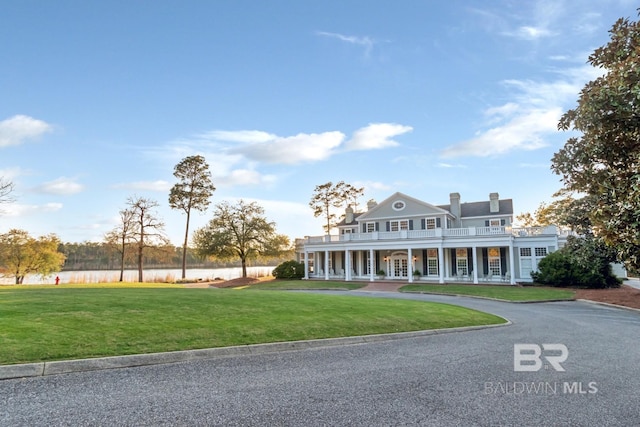 view of front of property featuring a front lawn, a water view, and a chimney