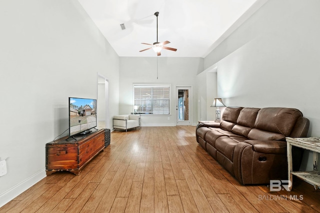 living room featuring ceiling fan, a towering ceiling, and light hardwood / wood-style floors