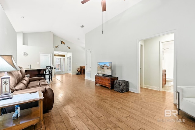 living room with ceiling fan, high vaulted ceiling, and light wood-type flooring