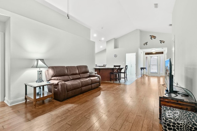 living room with high vaulted ceiling and light hardwood / wood-style floors