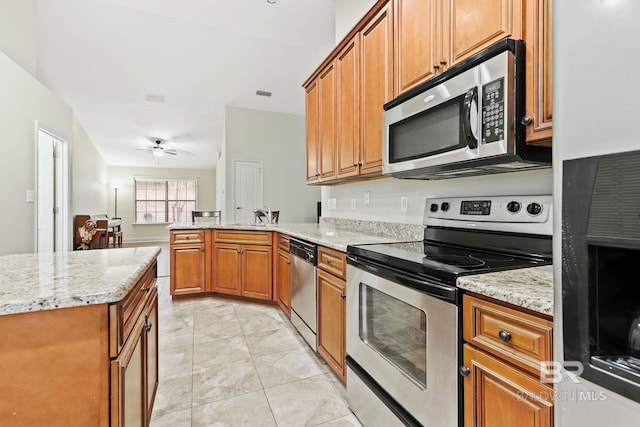 kitchen featuring kitchen peninsula, light tile patterned floors, ceiling fan, light stone counters, and stainless steel appliances