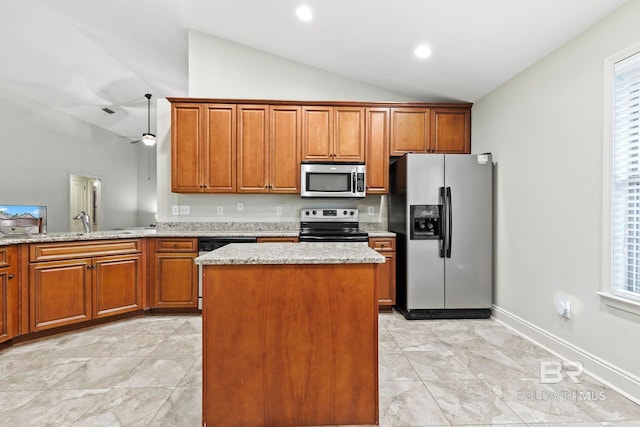 kitchen featuring appliances with stainless steel finishes, light stone countertops, vaulted ceiling, and plenty of natural light