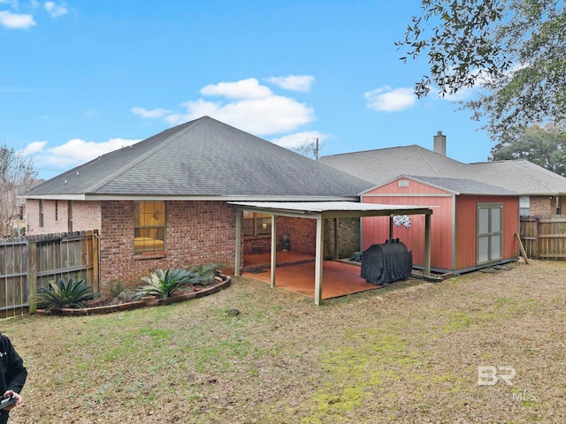 rear view of house with a patio area, a lawn, and a storage unit