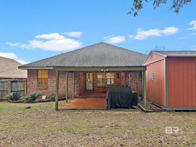 back of property with a patio, a lawn, and a shed