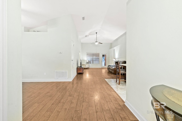 hall with lofted ceiling and light wood-type flooring