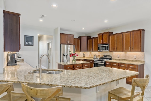 kitchen featuring a peninsula, a breakfast bar area, appliances with stainless steel finishes, and a sink