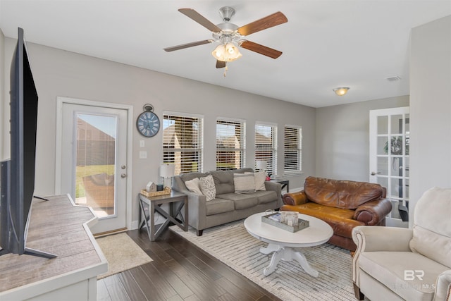 living area featuring baseboards, a ceiling fan, and dark wood-style flooring