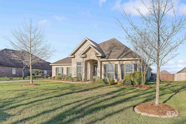 view of front of home featuring brick siding, roof with shingles, a front yard, and fence