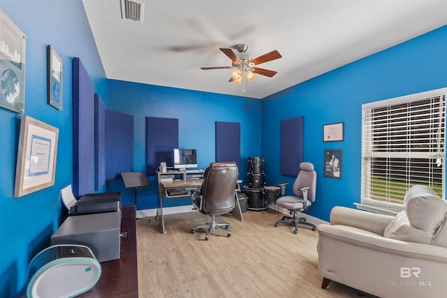 office area featuring visible vents, a textured ceiling, wood finished floors, baseboards, and ceiling fan