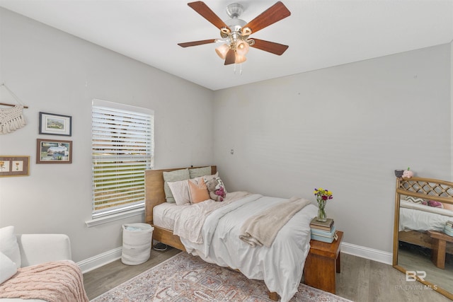 bedroom with a ceiling fan, wood finished floors, and baseboards