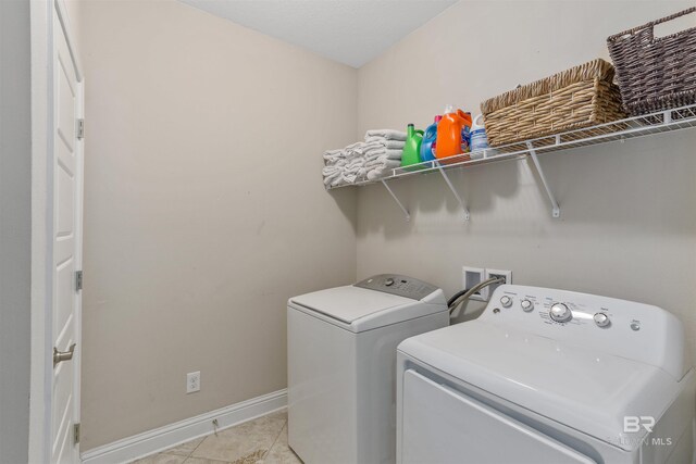 clothes washing area with light tile patterned floors, laundry area, independent washer and dryer, and baseboards