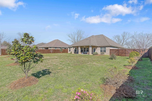 rear view of property featuring brick siding, a fenced backyard, and a lawn